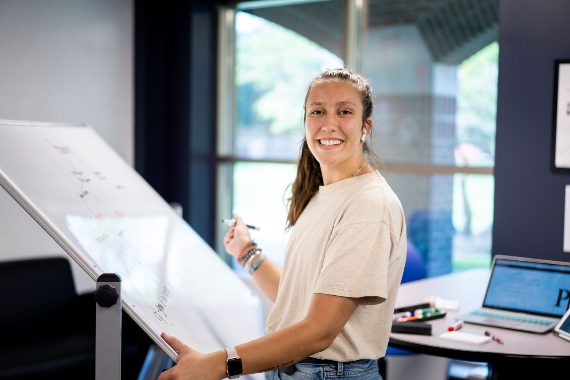 Student smiling while working at whiteboard